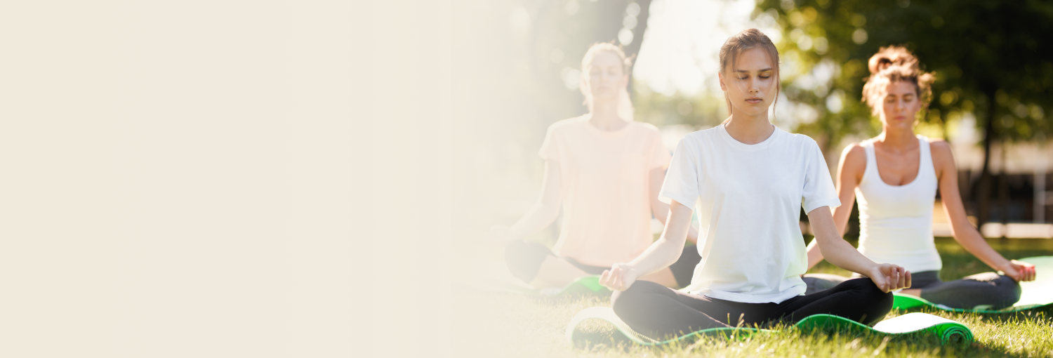 Women practicing meditation on yoga mats in sunny outdoor setting